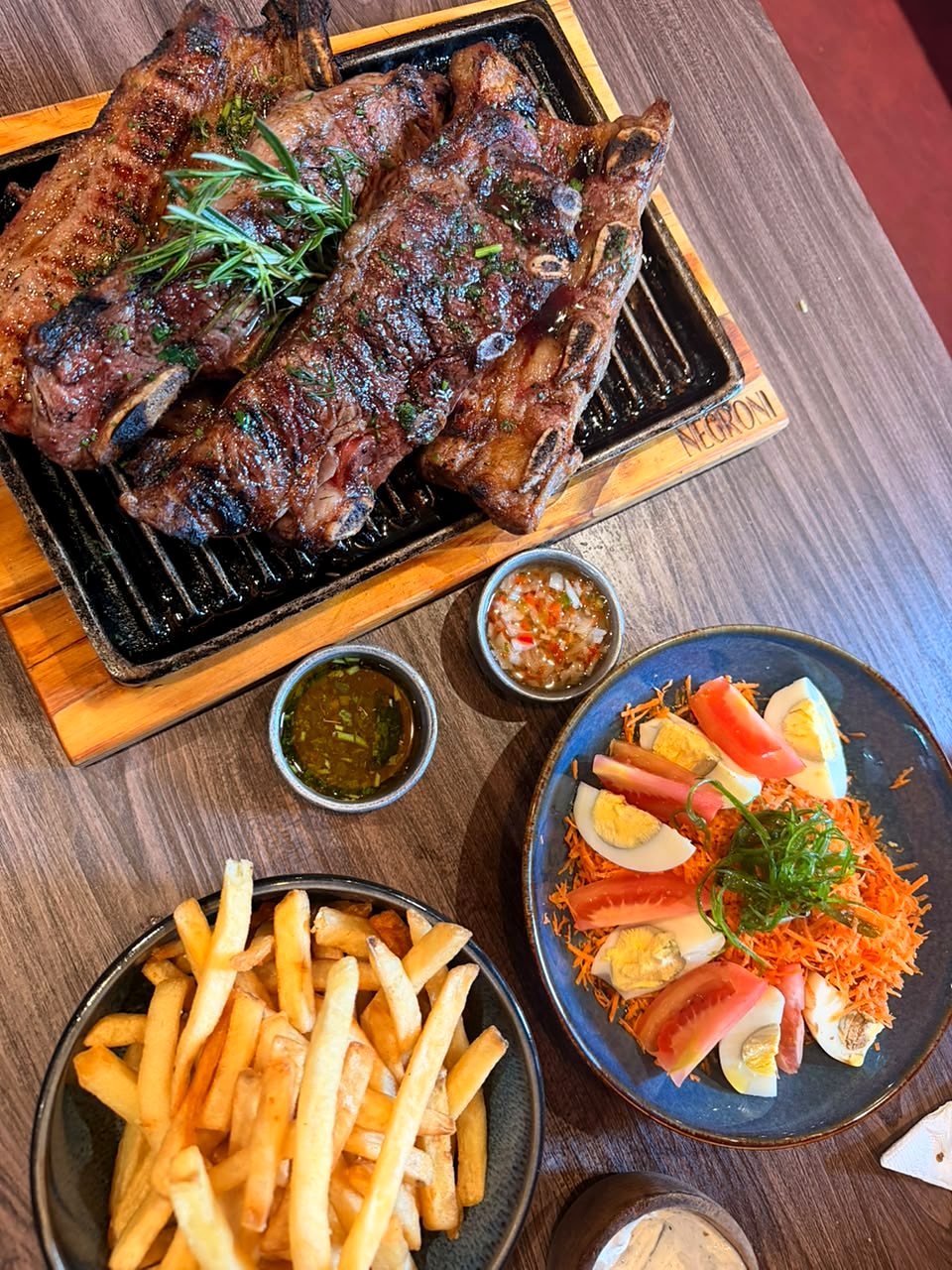 Asado a la parrilla con papas fritas, ensalada y salsas