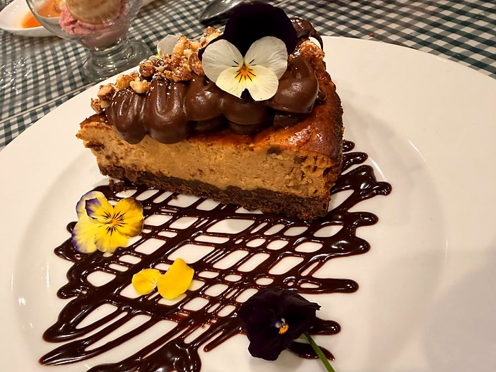Cheesecake con dulce de leche, salsa de chocolate y flores