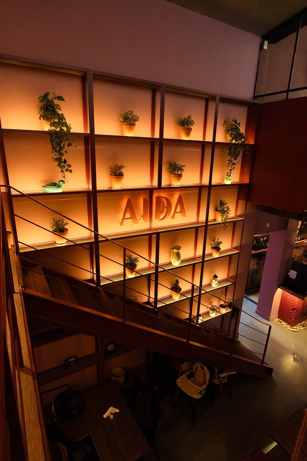 La escalera al primer piso, con la estantería iluminada y las letras AIDA