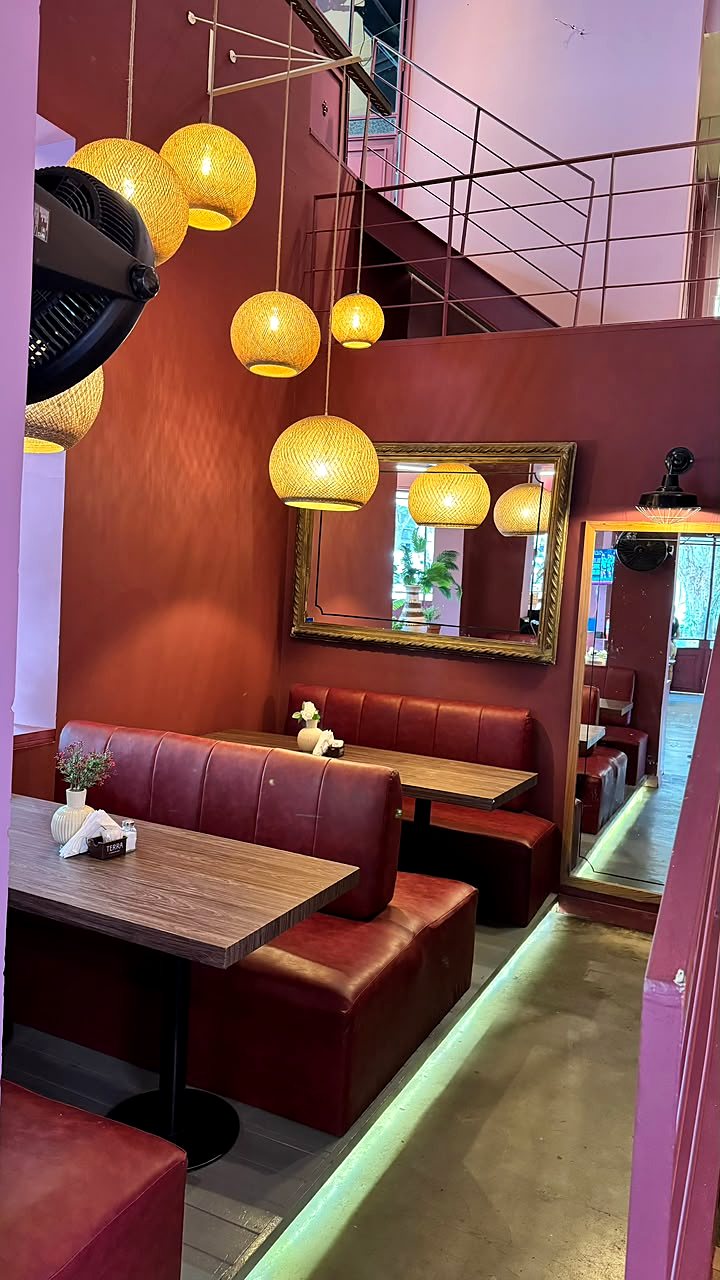 Un rincón del salón con boxes de cuero, un espejo dorado y lámparas de mimbre