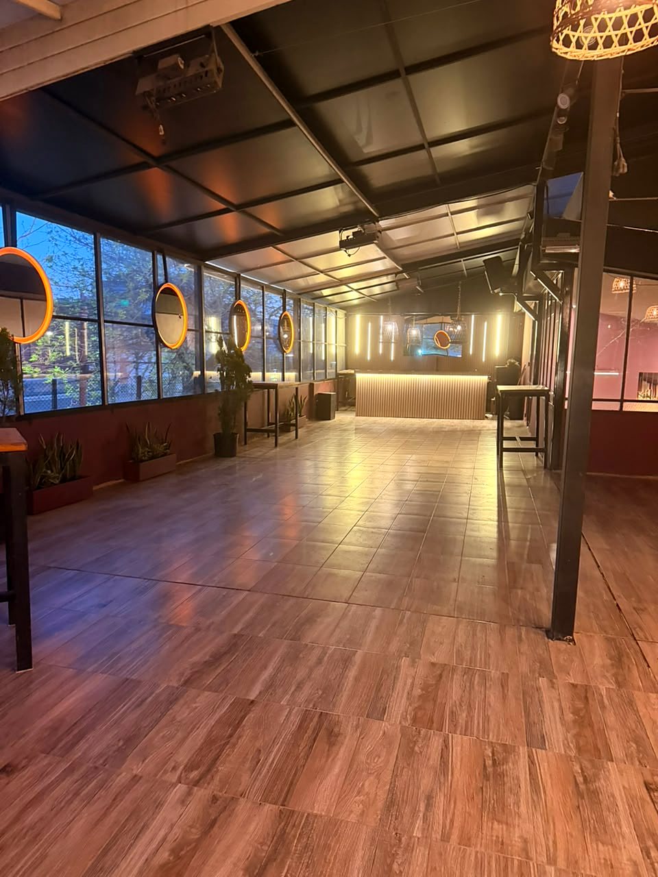 El salón vidriado del primer piso, con piso de madera y vista a los árboles