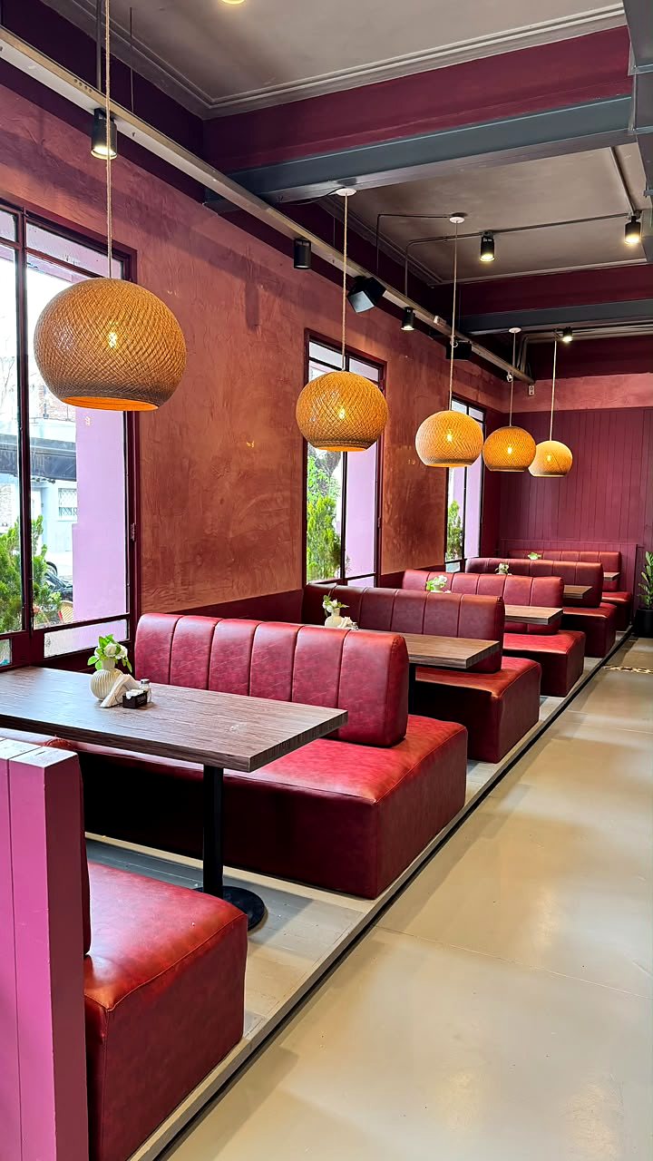 El salón principal con boxes de cuero rojo y lámparas de mimbre